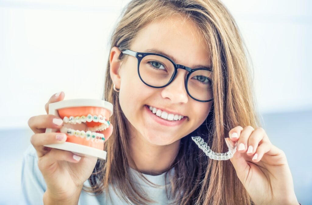 Girl comparing braces and Invisalign aligner at the dentist.