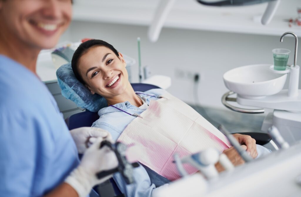 A dental patient in the chair before starting a routine dental cleaning, smiling.