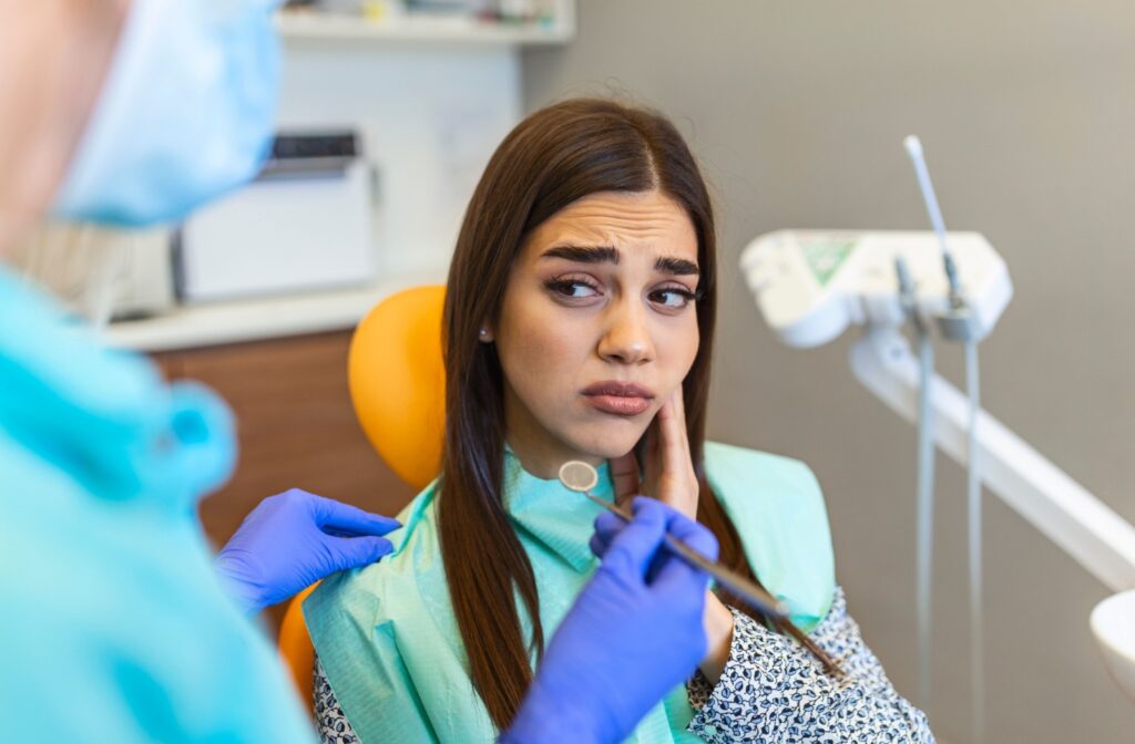 A patient at a dental appointment, holding their cheek due to tooth pain.