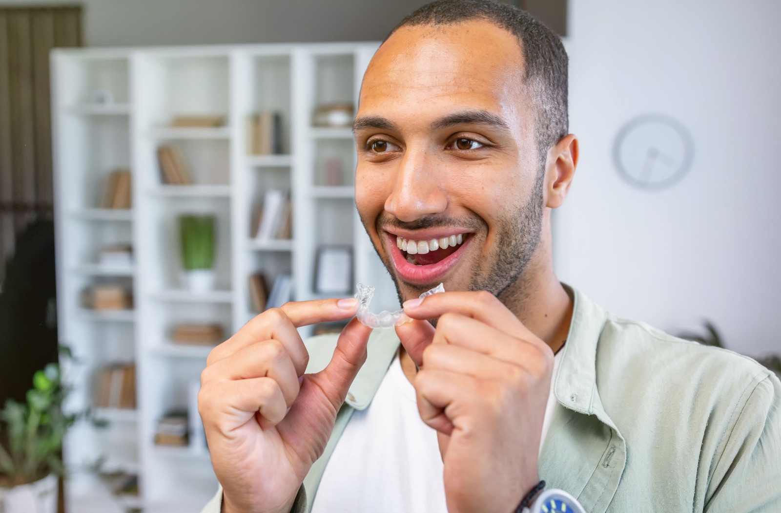 Person smiling with mouth open as they prepare to put their Invisalign tray into their mouth
