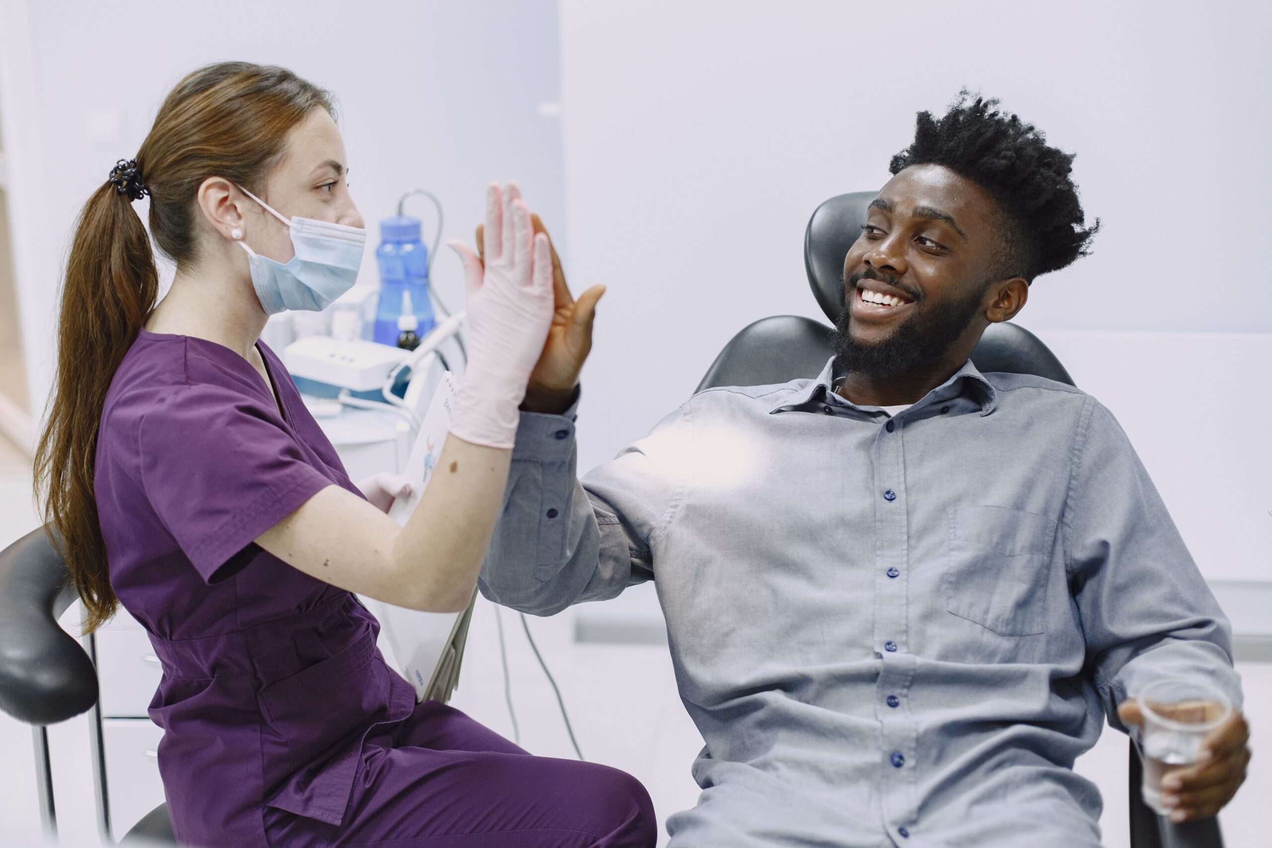 A smiling patient sharing a high five with a dental professional
