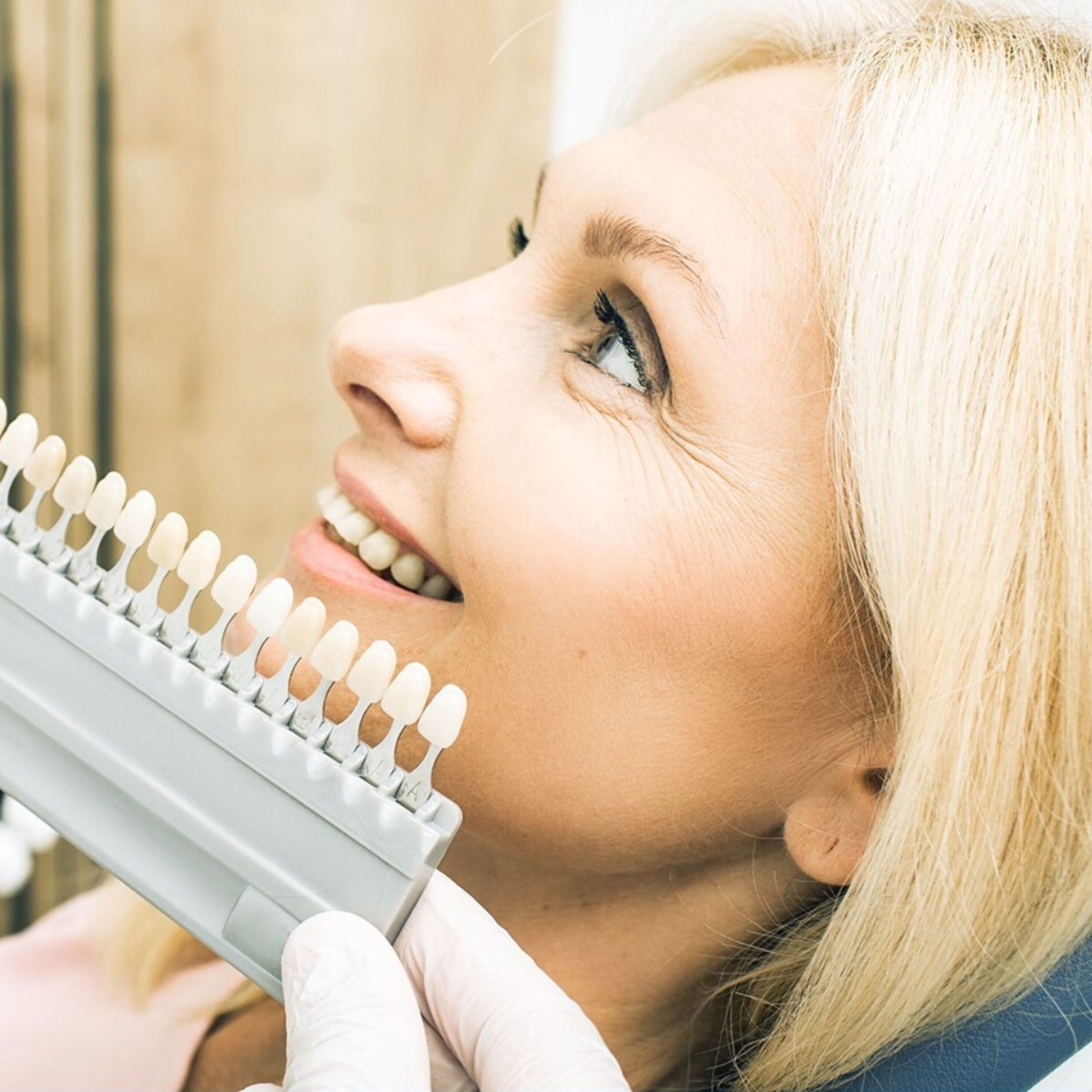 A patient smiling while looking into a mirror after dental care