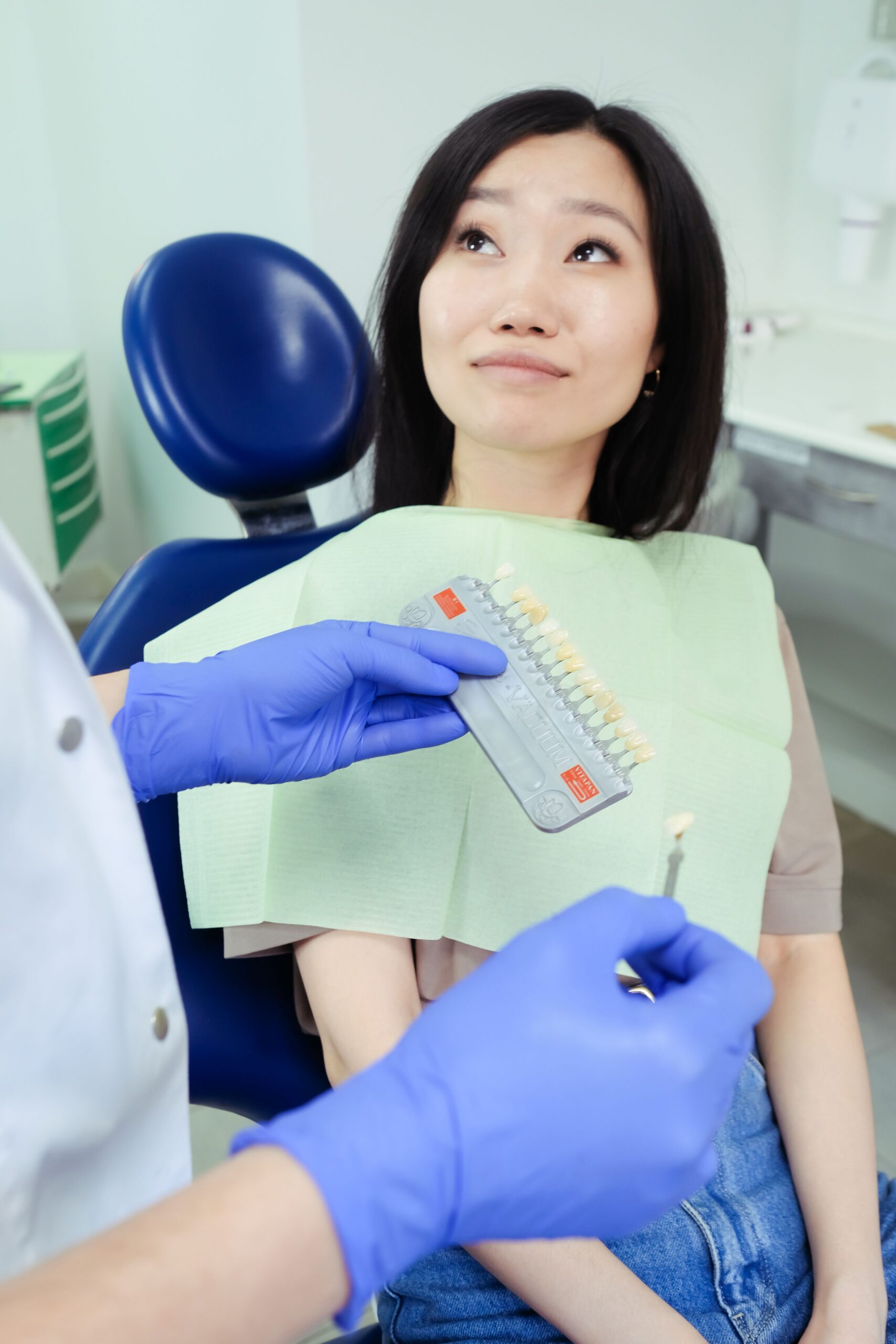 A smiling patient comparing tooth shades with a dental professional